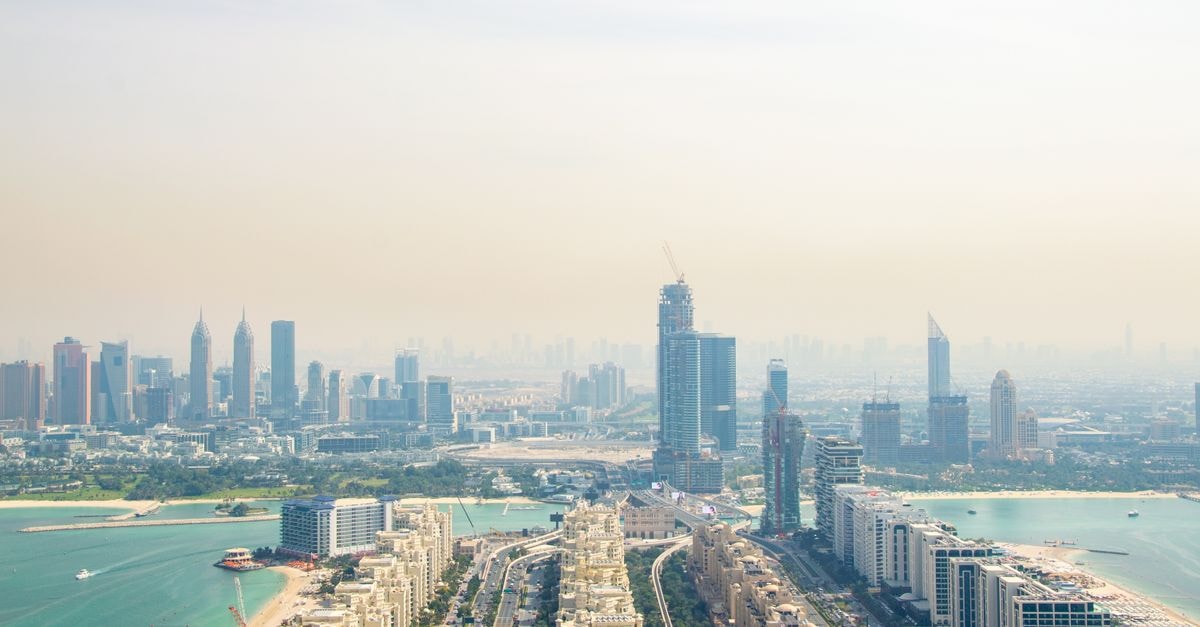 A scenic aerial view showcasing Dubai's impressive skyline and coastline with modern skyscrapers under hazy skies.
