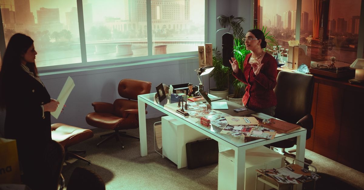 Two professional women engage in a business meeting in a modern Baghdad office with a view.