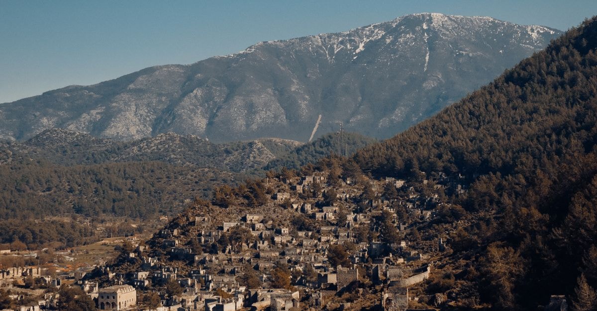 Talas Travel Guide: Valley History and Practical Connections Aerial view of the historic Kayaköy village nestled in mountainous terrain under a clear sky.