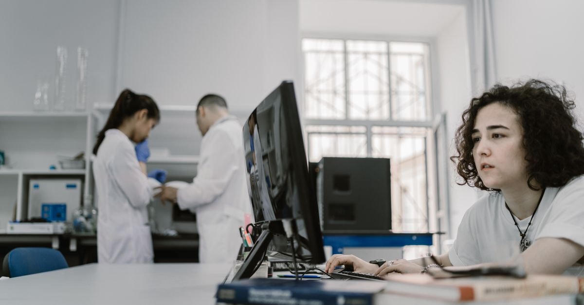 Quantum X Labs reports improved AI decoder results on Google's quantum error-correction dataset Focused woman working on a computer in a busy laboratory setting, showcasing teamwork and scientific research.