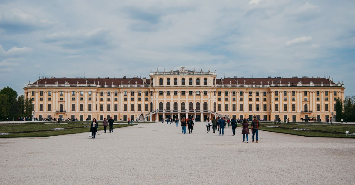 A Slow Vienna Travel Guide: Cafés, Palaces and Smart Transit People walking in front of Schonbrunn Palace in Vienna, Austria on a cloudy spring day.