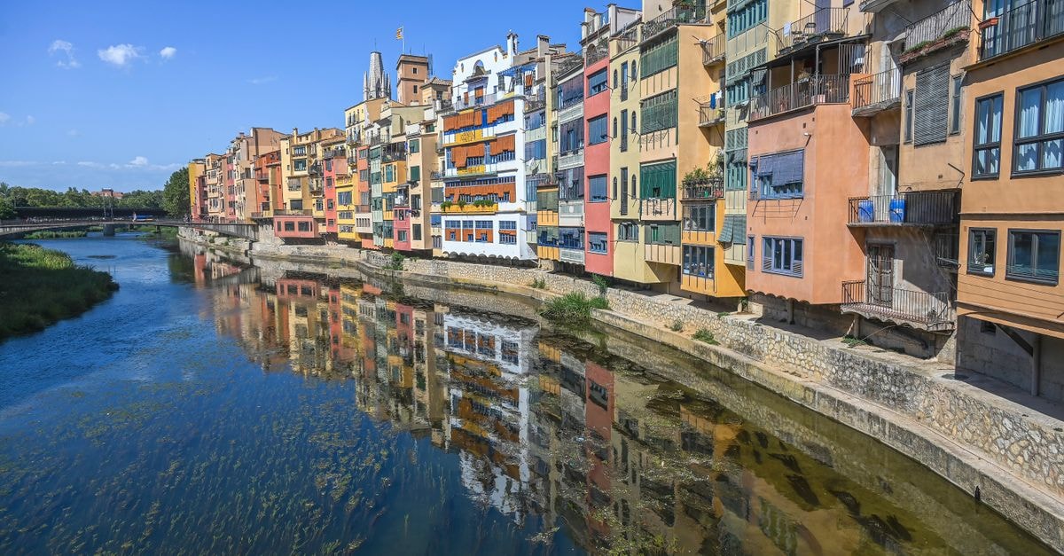 Vibrant riverfront view of colorful buildings along Onyar River in Girona, Spain.