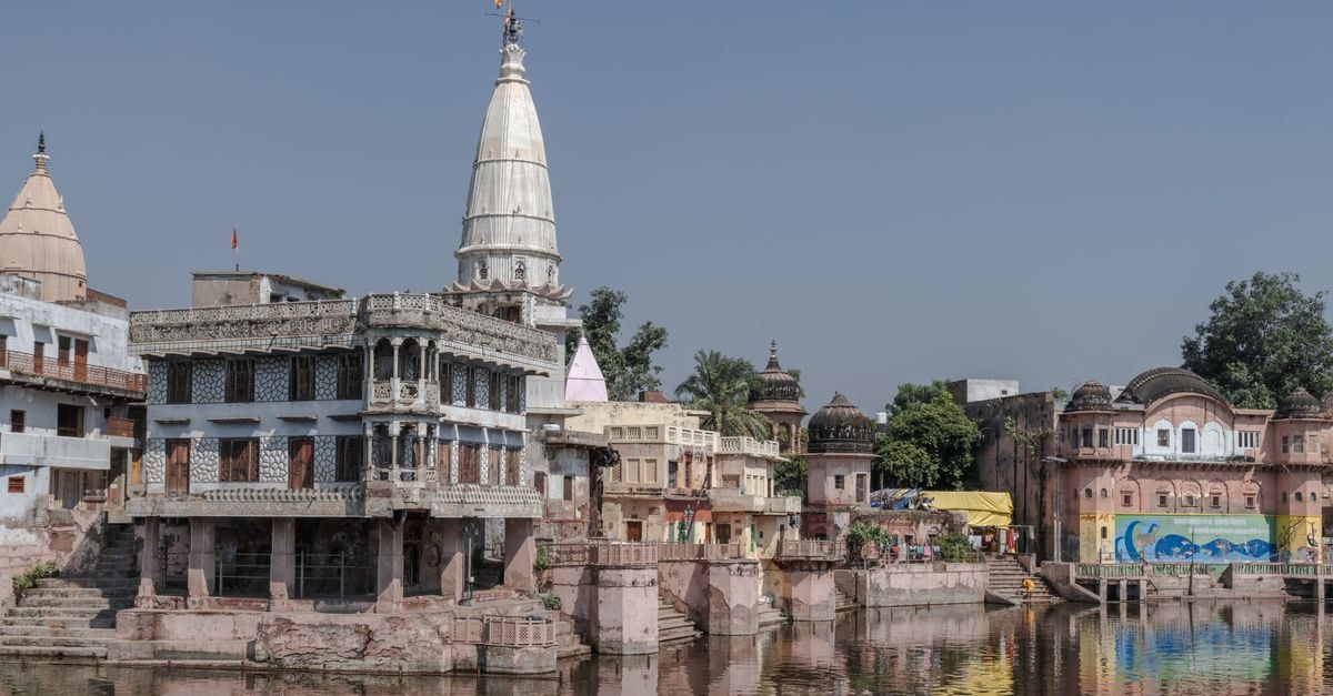 Satna Travel Guide: Temples, Heritage, and Slow Central India Scenic view of Govardhan's historic buildings reflecting in a serene water body in Uttar Pradesh, India.