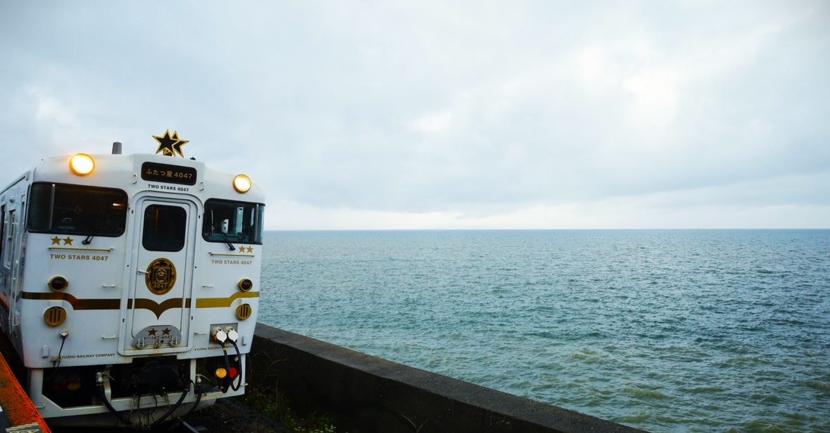 Nagasaki travel guide: harbor legacy, peace sites, and a distinctive food scene A scenic train on the coast of Higashisonogi, Japan, travels along the ocean under a cloudy sky.