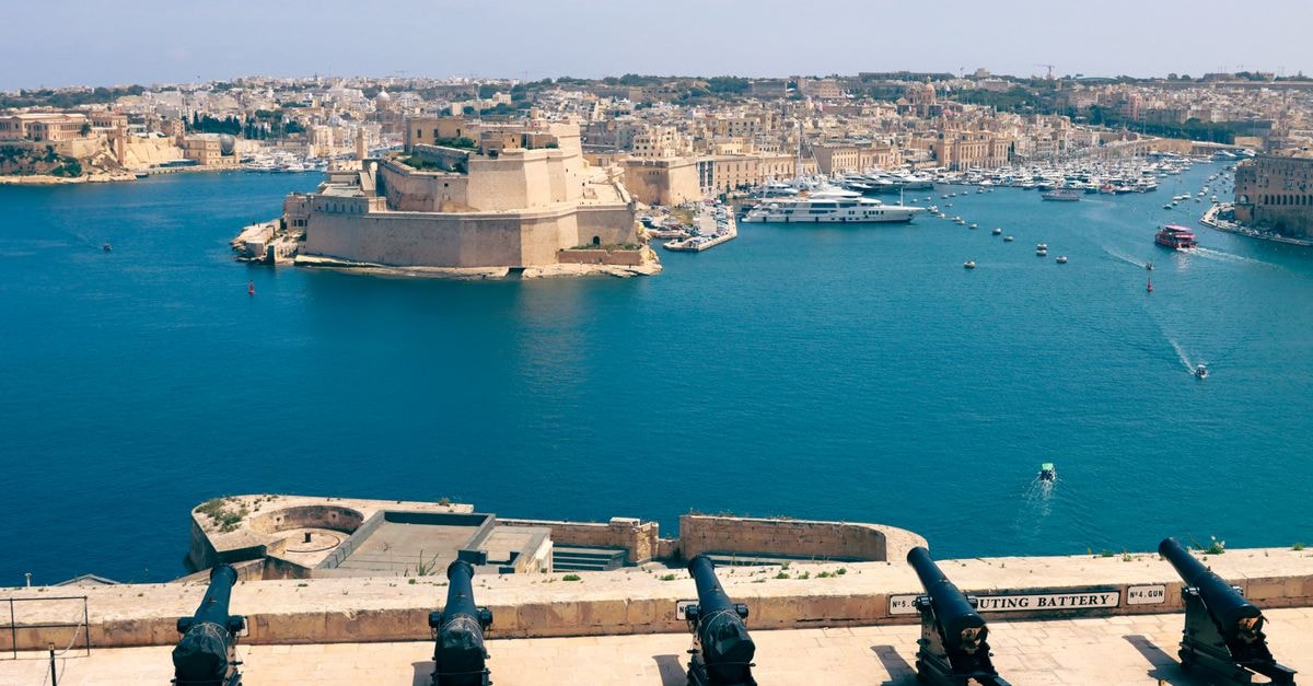 A stunning view of Valletta's harbor and fortifications with historic cannons in Malta.