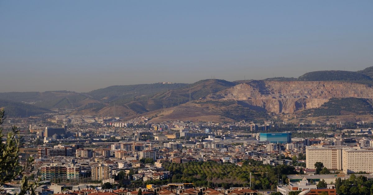 Les 2 Palmiers in Tizi Ouzou: A Roadside Stay on RN 25 Expansive view of İzmir cityscape against a backdrop of mountains under clear skies.