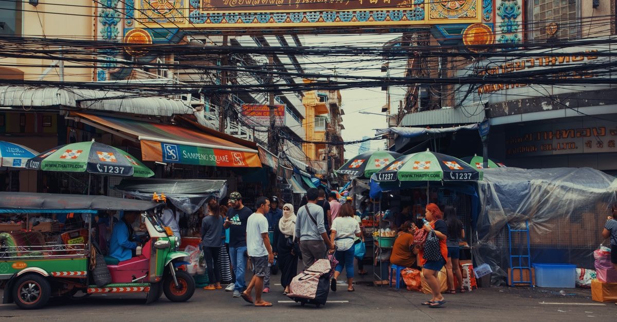 Fier Travel Guide: Markets, Daily Life and Getting Around A lively street market bustling with vendors and pedestrians under colorful signage.