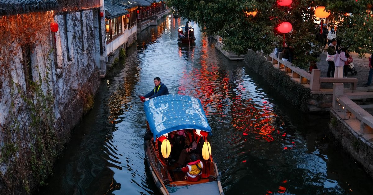 Suzhou Travel Guide: Gardens, Canals and a Squirrel-Shaped Fish Charming evening canal ride with traditional boat and red lanterns in Suzhou, Jiangsu, China.