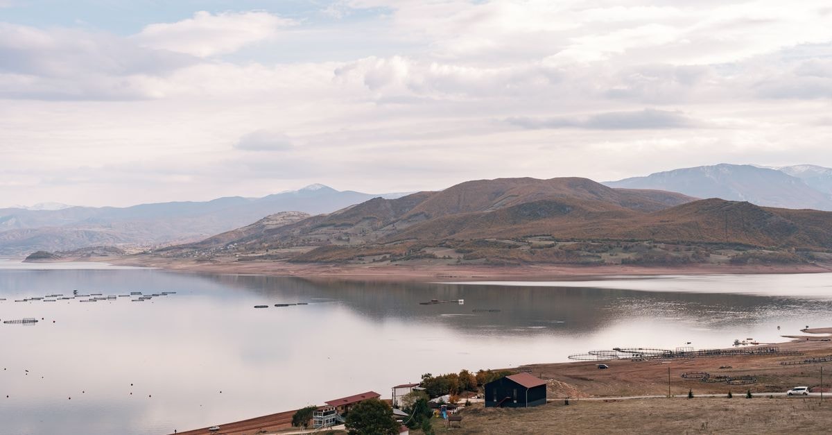 Tranquil mountain lake with reflective water and overcast sky.