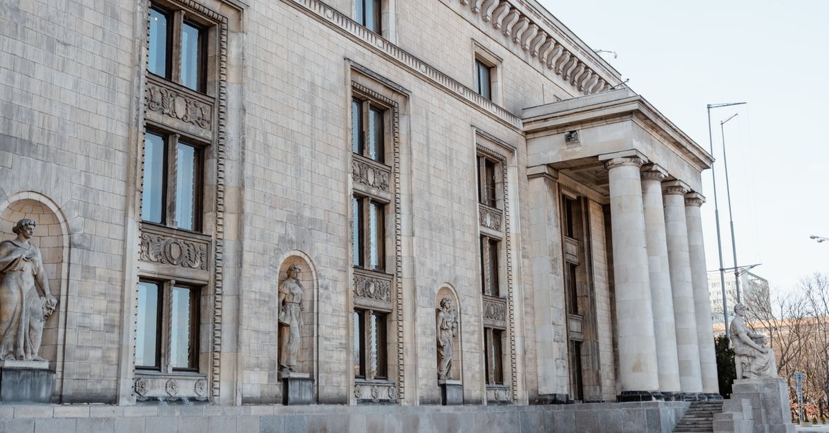 Historic neoclassical building facade with statues and columns in a city.