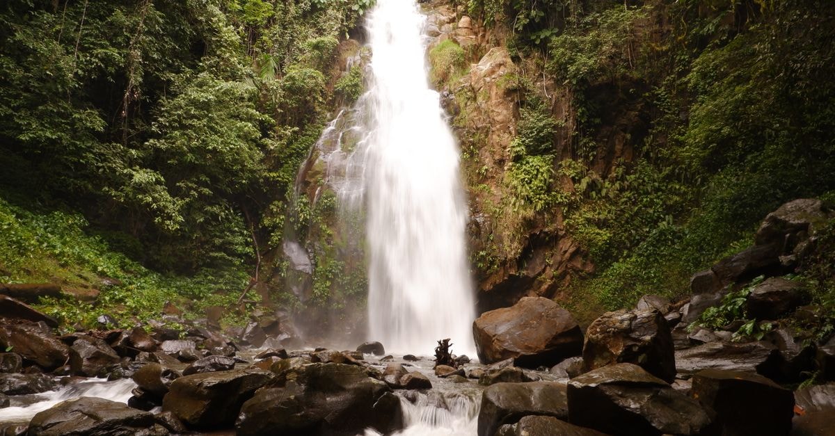 Butuan Travel Guide: Heritage, Rivers, and Northern Mindanao Breathtaking view of a waterfall cascading in a lush tropical forest, Northern Mindanao. Perfect for nature lovers.