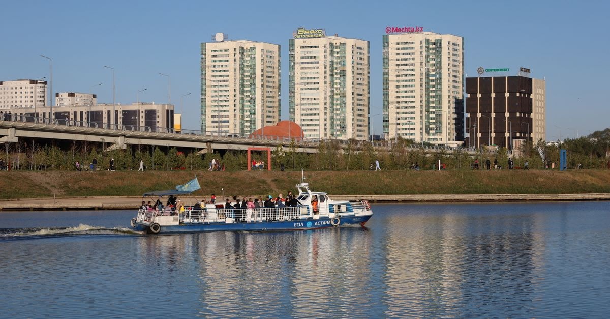 King Hotel Astana: A 475-Room Stay in the Capital's Cultural Heart Ferry boat sailing on a river with modern buildings in the background, capturing urban life.