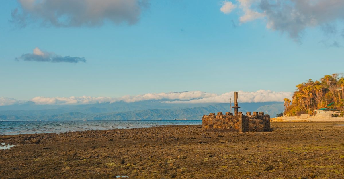 Explore ancient stone ruins on a tranquil coast under a bright blue sky.