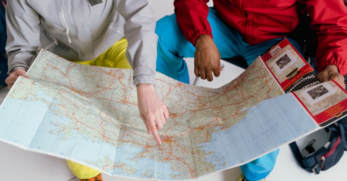 Leicester Travel Guide for August 2026: Planning Tips and Costs Two travelers examining a detailed map for a winter hiking adventure.