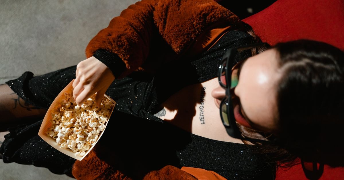 Zurich Film Festival Sets Galas Including 'I Play Rocky' and 'Josephine' Woman in winter clothing enjoying popcorn while sitting in a theater seat.