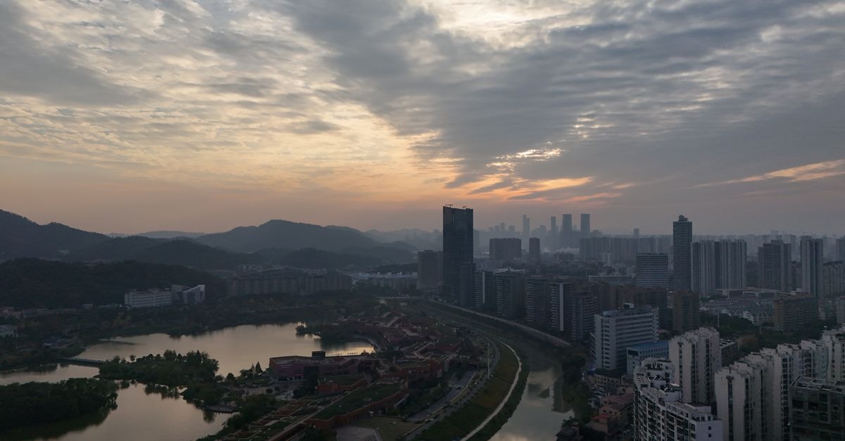 中國長沙的空拍夜景，呈現都市天際線與河流在夕陽下的景色。