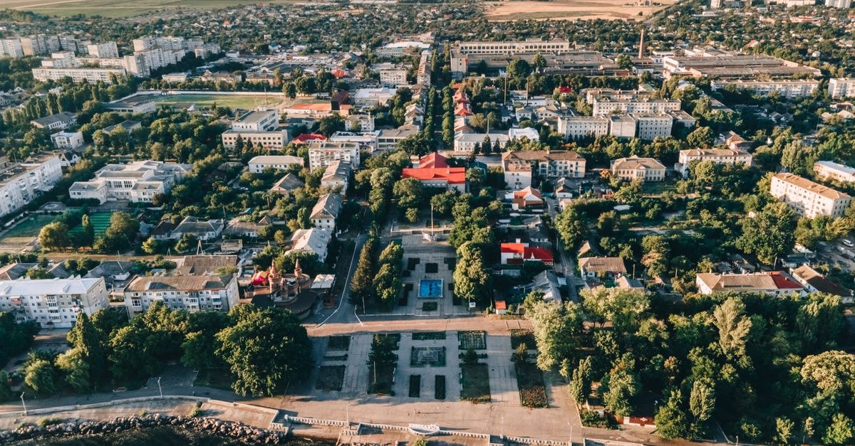 Radisson Blu Hotel, Kaliningrad — Baltic Heritage on Victory Square Aerial view of a peaceful coastal town showcasing greenery, buildings, and a waterfront area during summer.