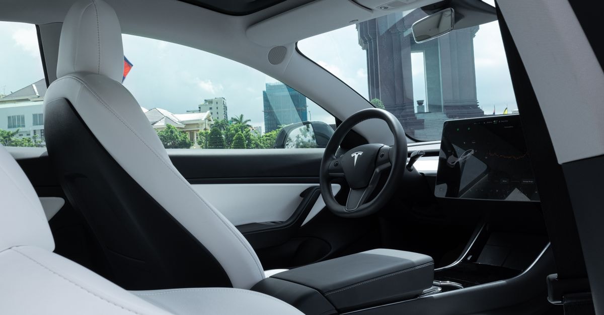 Tesla Launches Cybercab in Austin Without Human Controls Luxurious interior of a modern electric car with white leather seats and advanced dashboard features.