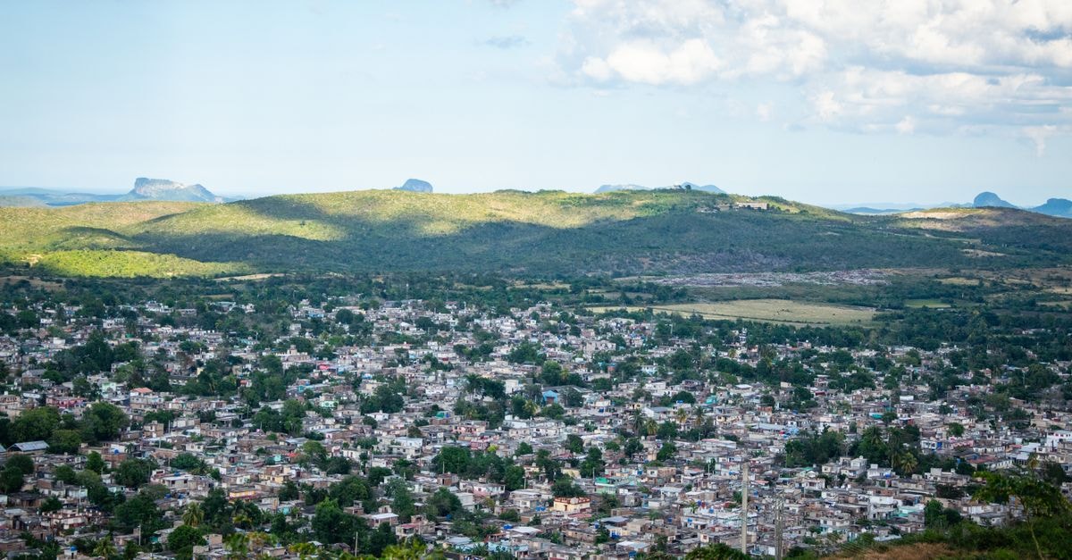 Hotel San Diego Valadares, Governador Valadares — Morada do Acampamento Address Aerial view of a sprawling cityscape amidst lush green hills under a partly cloudy sky.