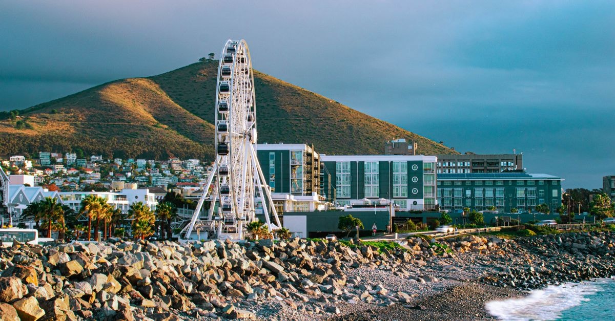 Windhoek Travel Guide: Planning Tips, Costs and Things to Do A picturesque view of Cape Town's coastline featuring the Cape Wheel, mountains, and cloudy skies.