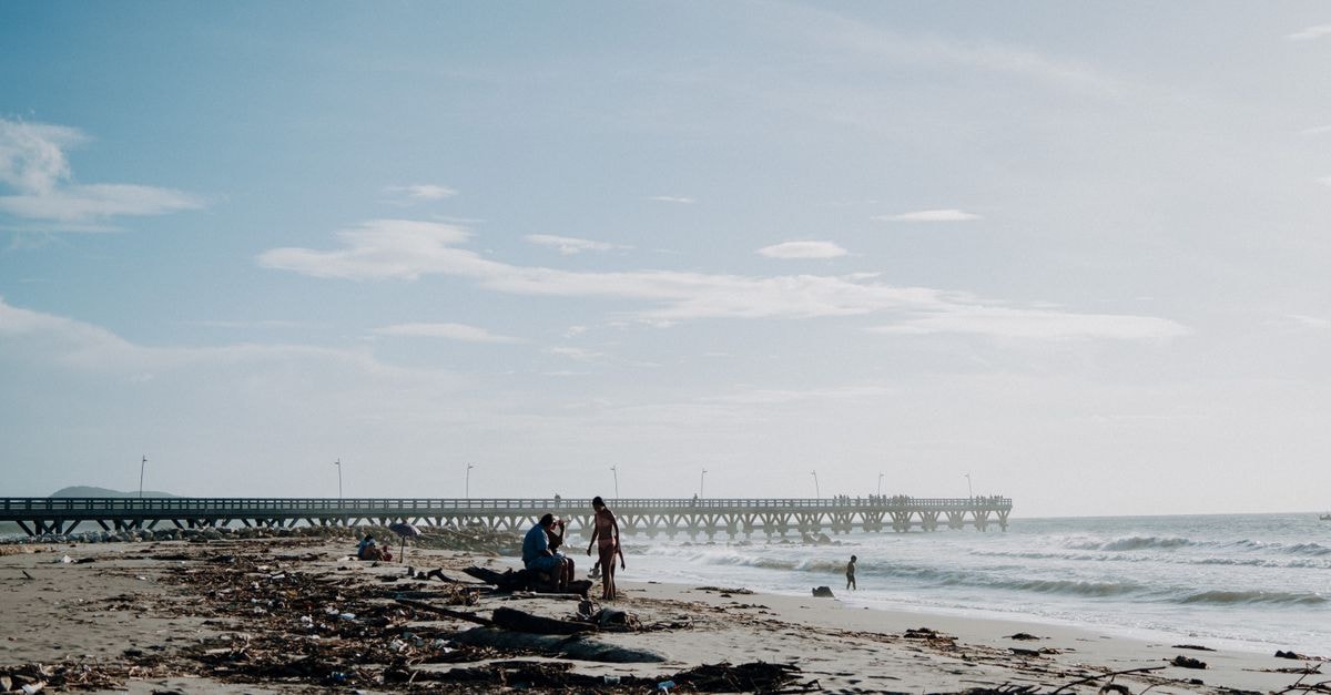 A slow travel guide to Santa Teresa del Tuy Scenic view of a beach with a dock at Puerto Colombia, ideal for travel enthusiasts.