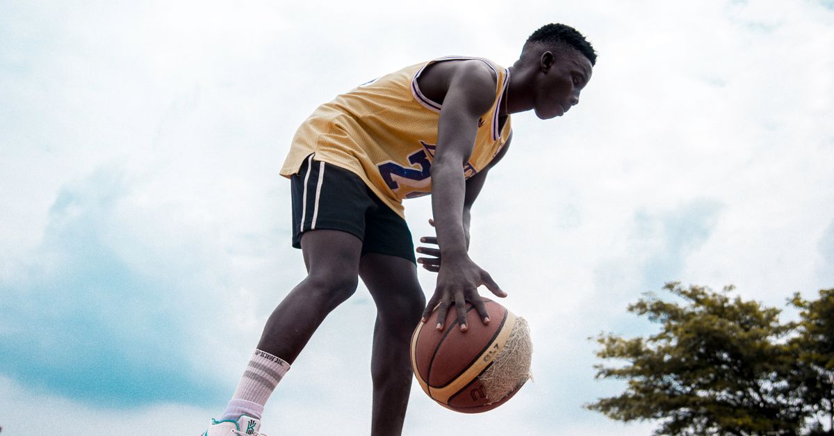 Young basketball player dribbling outdoors, showcasing skill and determination.
