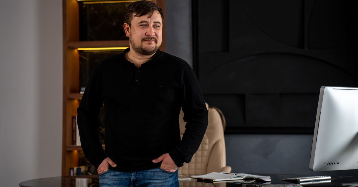 A man stands confidently by his desk in a stylish, modern office setting.