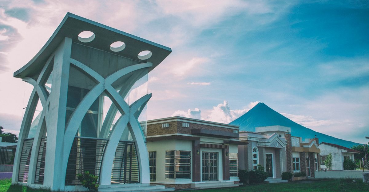 Cotabato Diamond Hotel, Cotabato City — A Practical Stop in the City Center A striking modern building juxtaposed with the iconic Mayon Volcano under a bright sky.