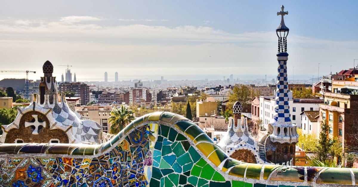 View of Barcelona from Park Güell showcasing mosaic architecture and city skyline.