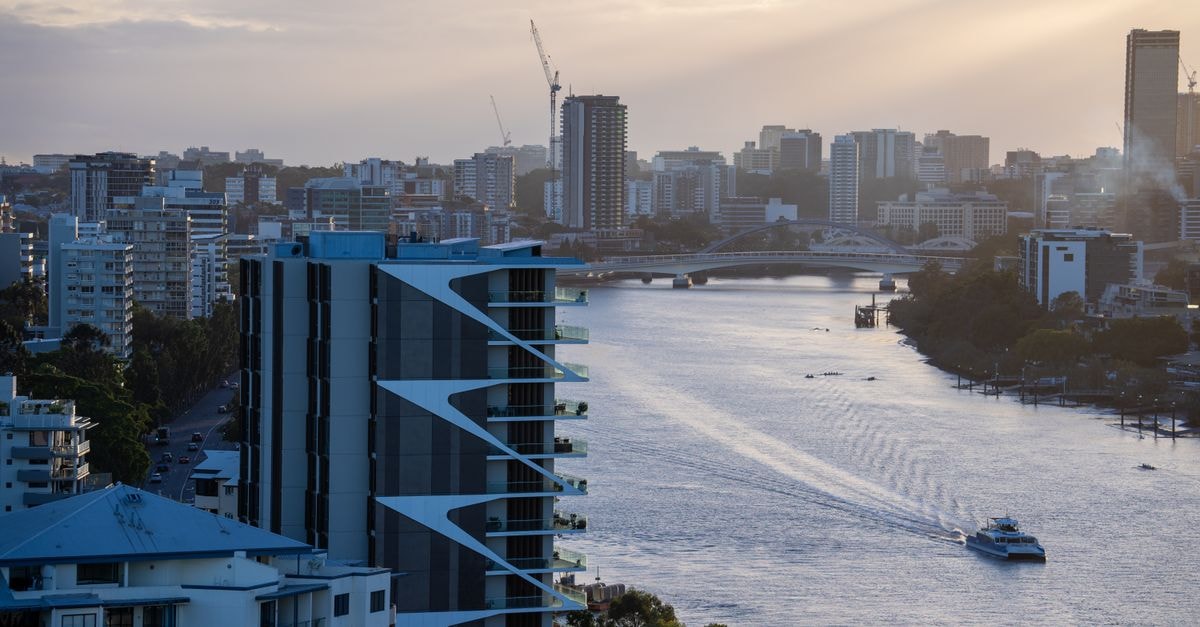 A beautiful view of Brisbane's river and skyline at sunset featuring modern architecture and boats.