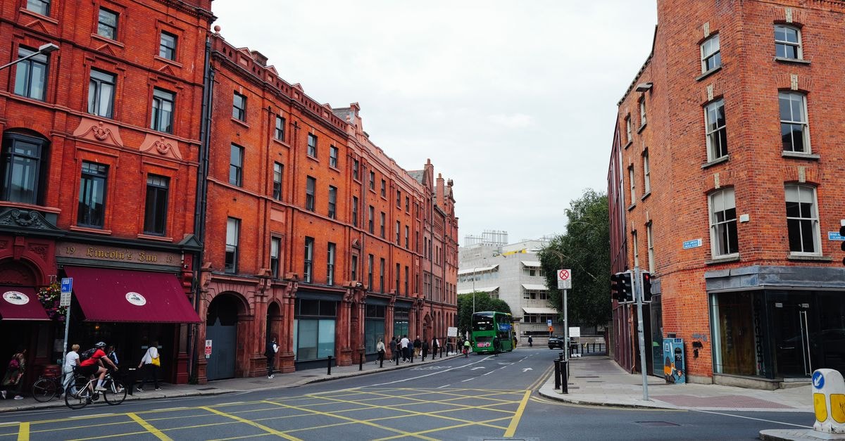 A bustling urban street with red brick buildings and a green bus passing by.