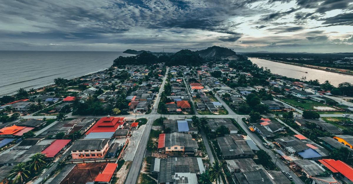 Miri Travel Guide: Coastal City Adventures in Sarawak Drone view of small town with buildings and roads near green plants located near calm water under cloudy sky in summer day