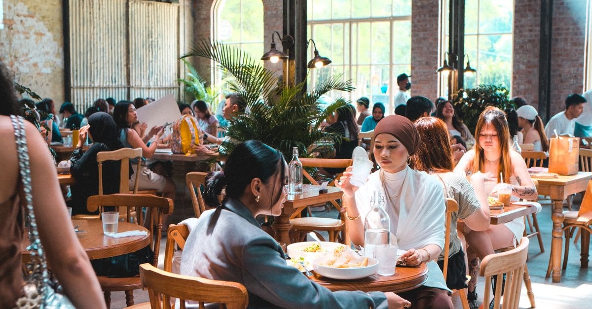 Cambridge Travel Guide: Getting Around and Eating Well Capture of a bustling café scene in Kuala Lumpur, showcasing diverse interactions and vibrant dining atmosphere.