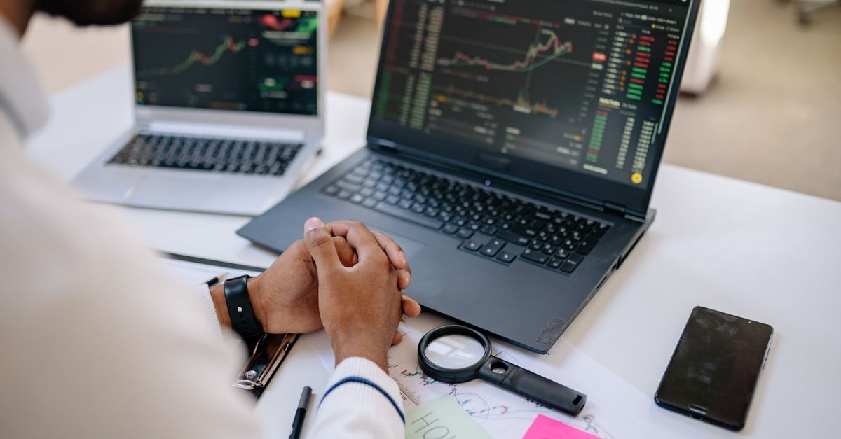 Blackstone to sell up to $1.25 billion stake in India's Knowledge Realty Trust Business professional analyzing stock market data on dual laptops in an office.