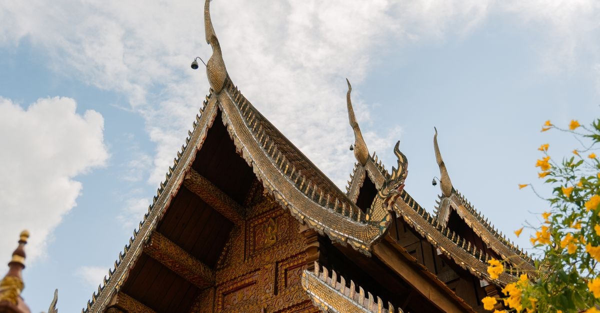 De Lanna Hotel in Chiang Mai: Lanna-Style Retreat Inside the Old City Beautifully ornate temple roof with traditional Thai architecture in Chiang Mai under a clear blue sky.