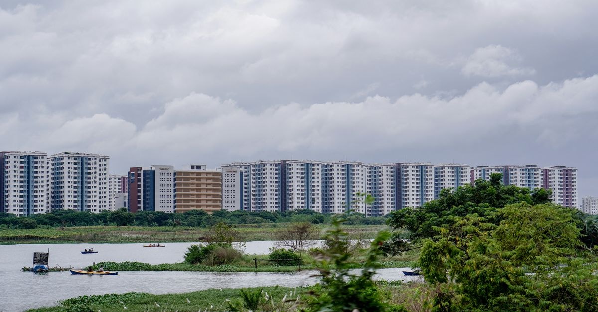 Youth Hostel Kolkata in Panihati: A Friendly Backpacker Stop High-rise buildings along a peaceful river under cloudy skies.