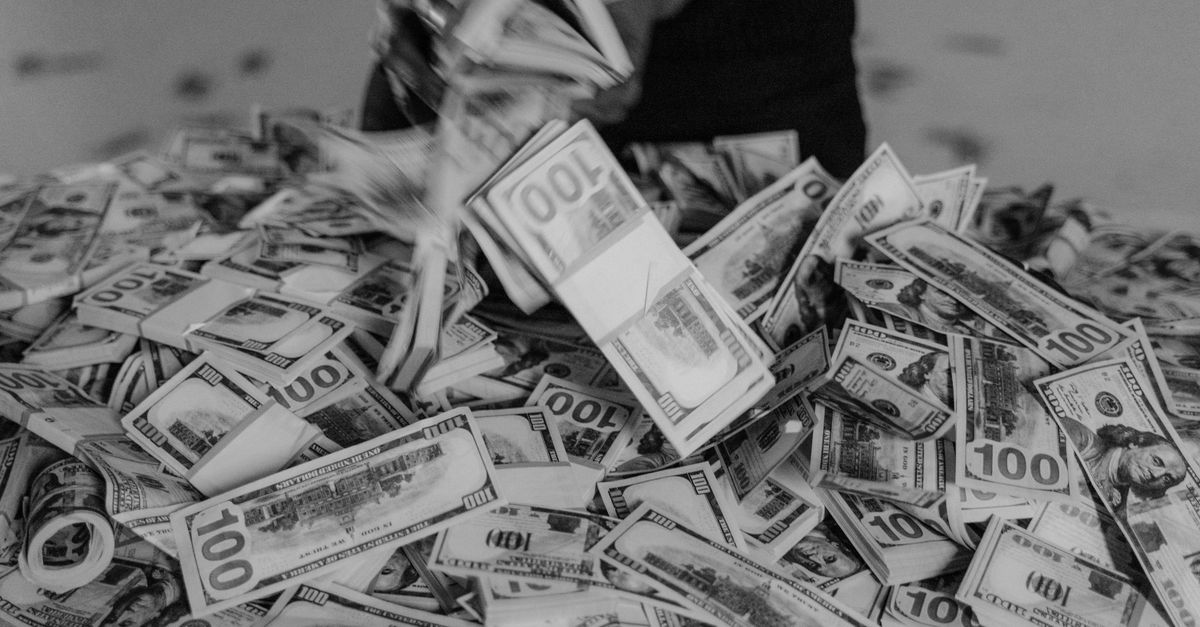 Silver edges above $58 as dollar retreats, but Middle East tensions and Fed hike bets cap gains A large pile of hundred dollar bills being handled, creating a sense of wealth and abundance.