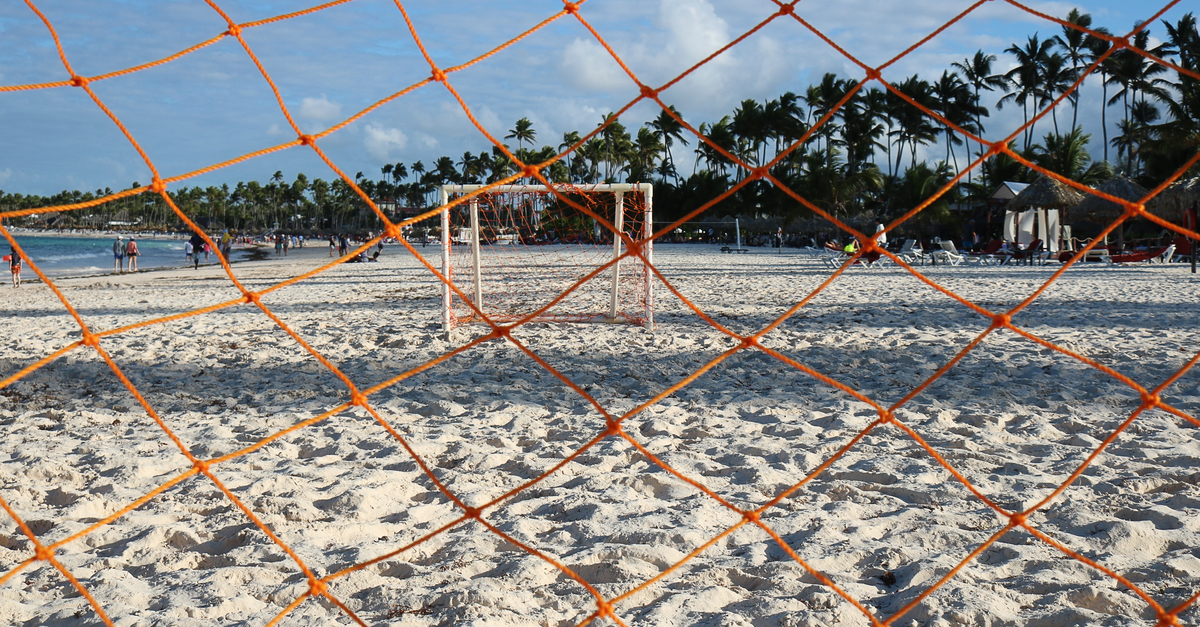 Discover La Romana: A Quiet Caribbean Travel Guide Orange soccer net on a sandy beach in Punta Cana, Dominican Republic, perfect for a tropical sports setting.
