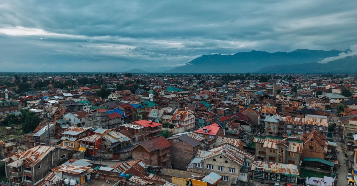 Stunning aerial view of Srinagar city with dramatic clouds and distant mountains, capturing the vibrant urban landscape.