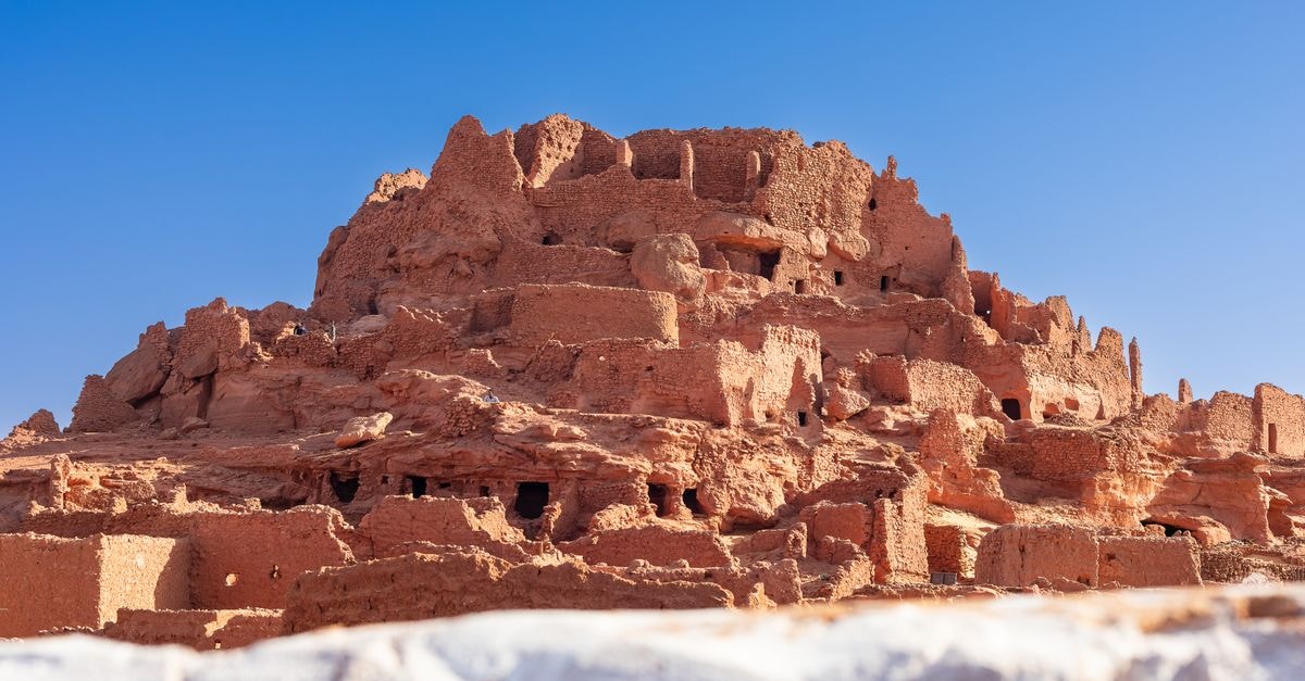Explore the stunning ancient ruins of Timimoun with clear blue skies in Algeria's desert landscape.