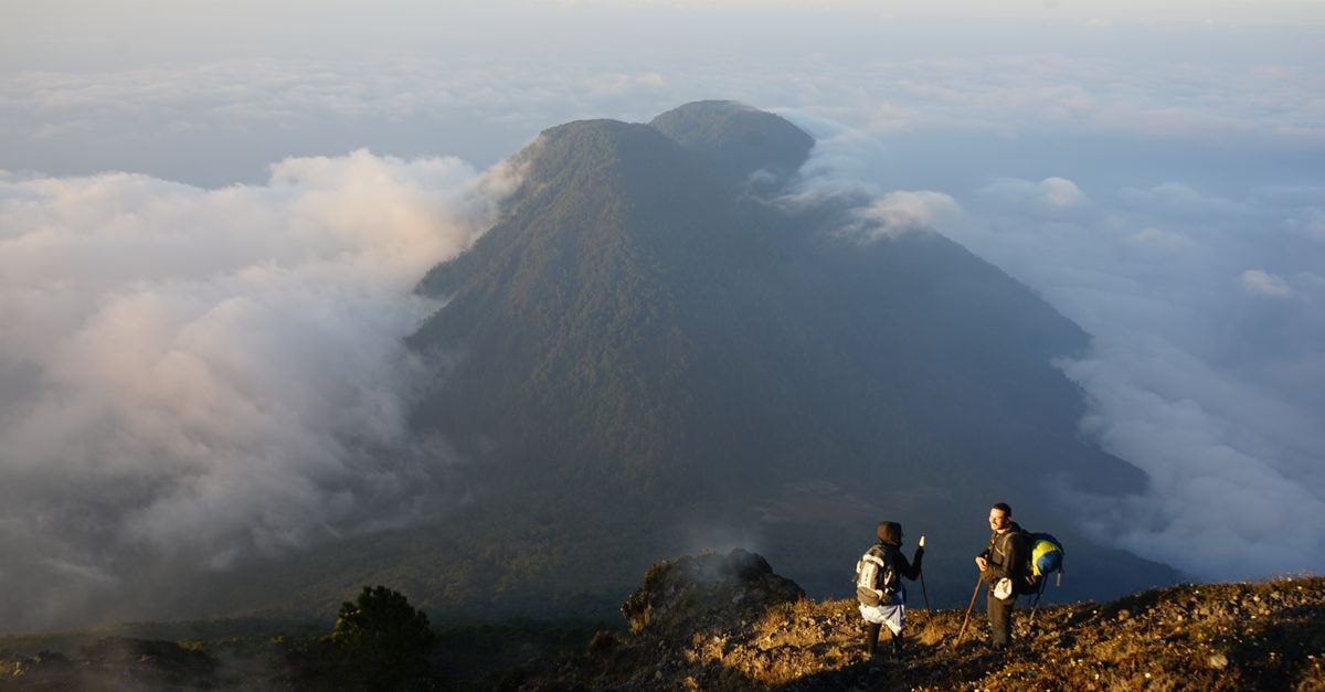 Two hikers enjoying a breathtaking view from the Acatenango Volcano summit in Sololá, Guatemala.