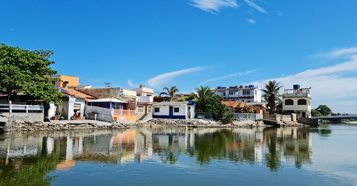 Salvaleón de Higüey Travel Guide: Heritage, Faith, and the Yuma River Beautiful view of colorful houses by the water with clear reflections under a blue sky.