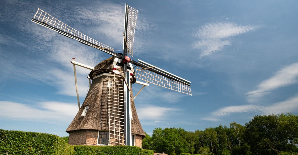 Assen Travel Guide: Slow Days in Drenthe's Easygoing Capital Low angle of aged of big mill in green plants against cloudy sky at sunny day