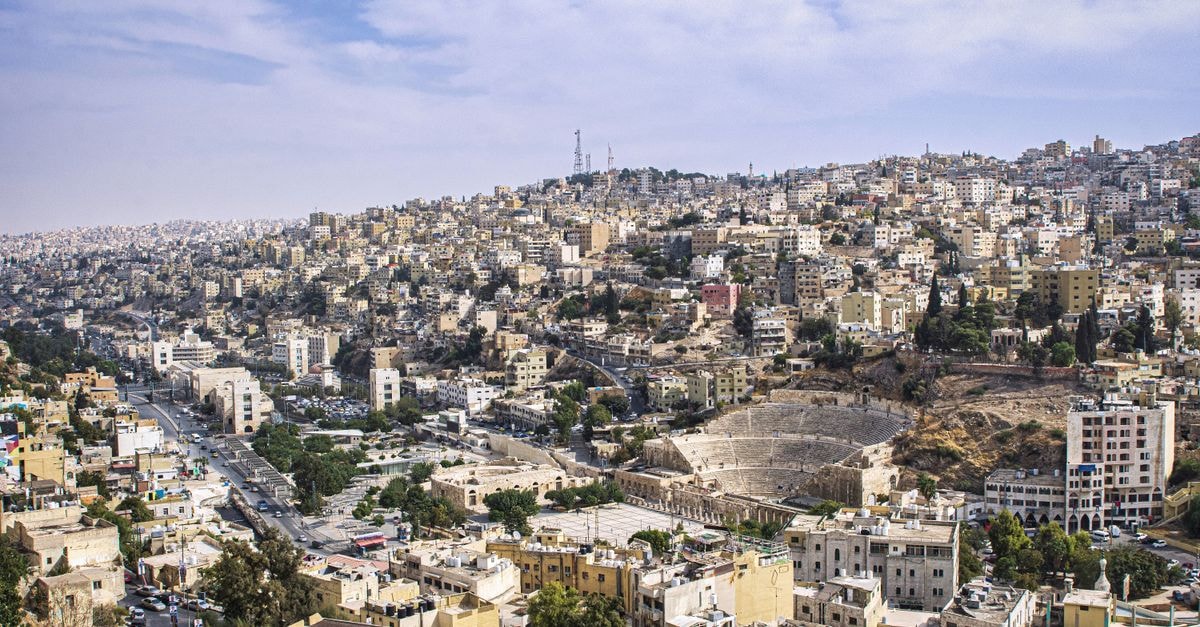 Explore Amman's urban landscape and ancient Roman amphitheater in a stunning aerial view.