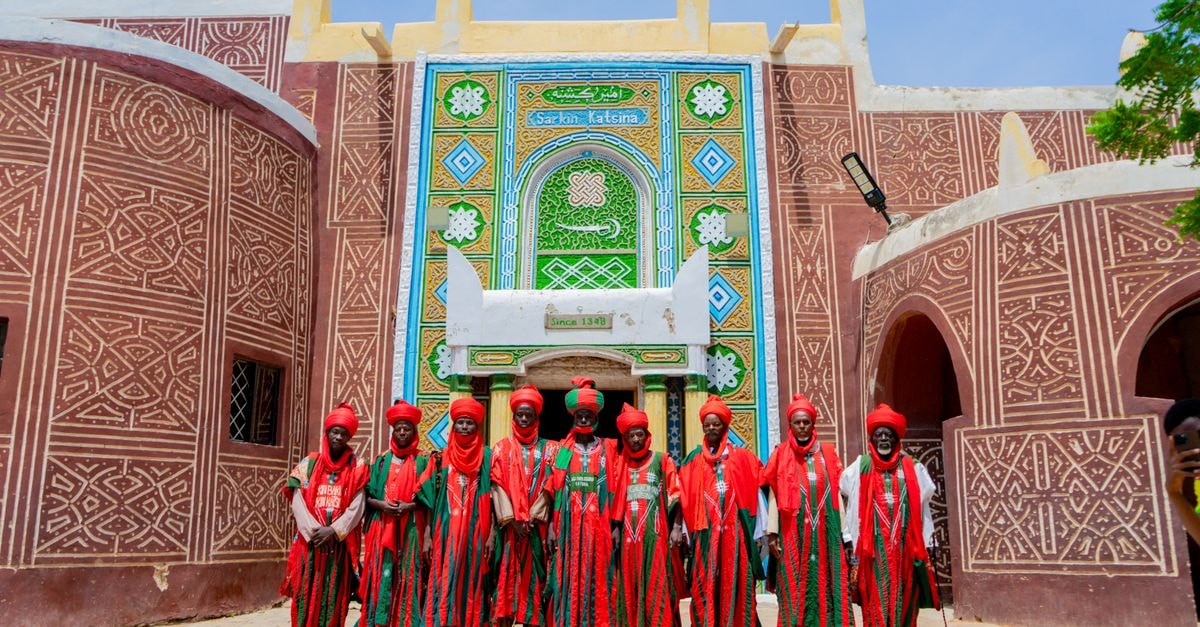 Doba Travel Guide: Gateway to Logone Oriental's Living Traditions Vibrant traditional attire in front of historic architecture in Katsina, Nigeria.
