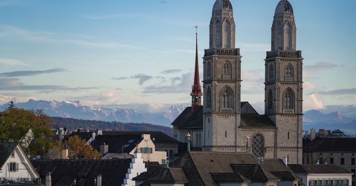 Hotel St. Gotthard in Zurich — Hospitality on Bahnhofstrasse Since 1889 Capture of Grossmünster Church with Swiss Alps in Zurich during daytime.