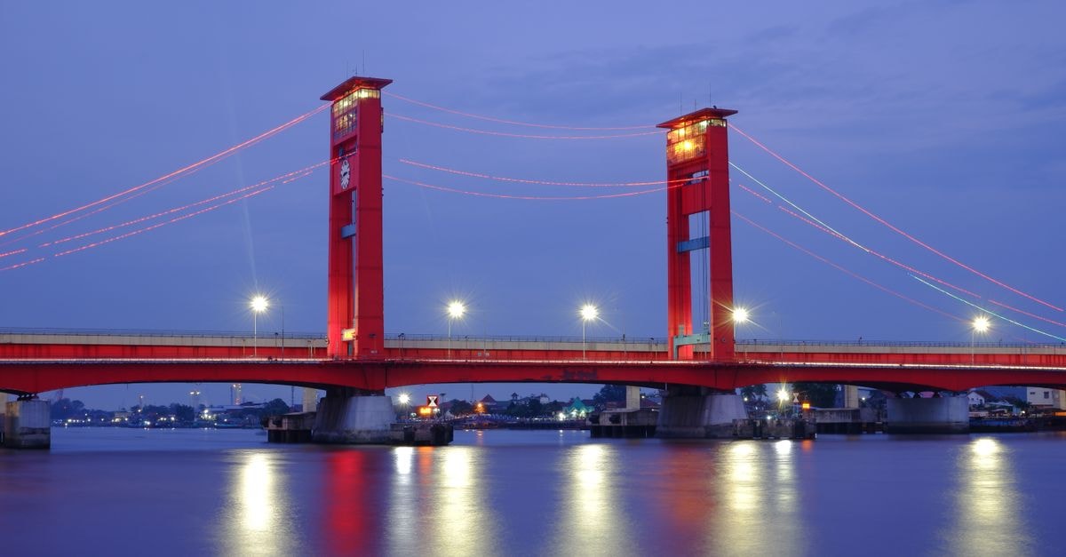 OYO 1282 Feodora Airport Hotel in Palembang: A Practical Stop Near Jalan Perindustrian Stunning night view of Ampera Bridge in Palembang, Indonesia with beautifully reflected lights.