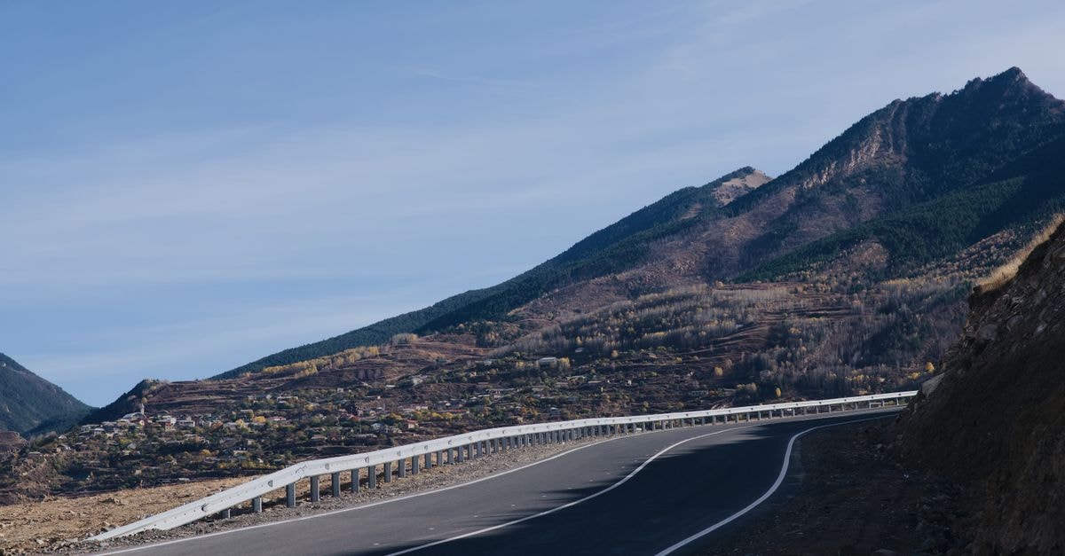 Haidong Travel Guide: Monasteries, Mountains, and the Yellow River A winding road curves through a mountainous landscape with a rustic village nestled below.