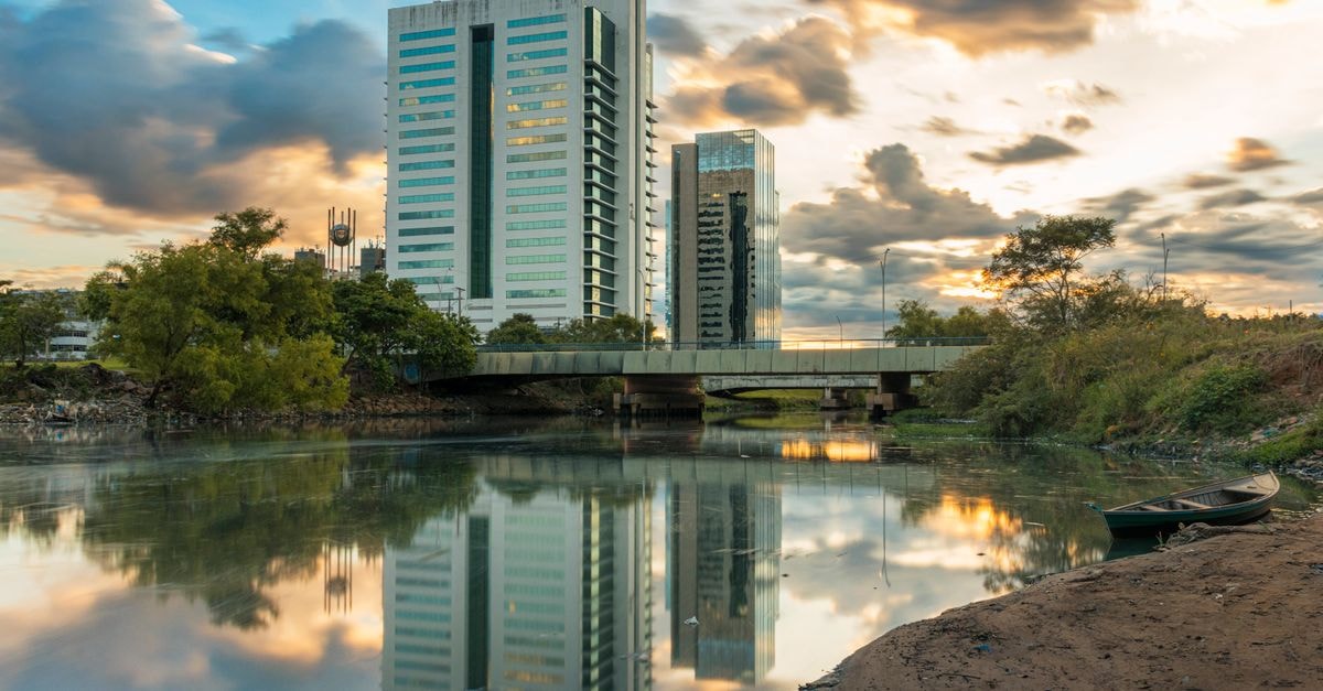 Cuiabá travel guide: heat, rivers, and a Pantanal mindset Captivating view of Porto Alegre's reflections in a river during sunset with clouds and modern architecture.