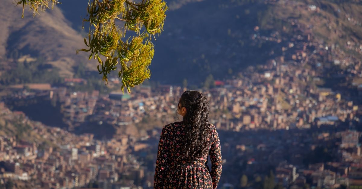 Los Ilinizas Hotel in Latacunga: Cozy Base Near La Catedral A woman in a floral dress gazes over the beautiful cityscape of Cusco, surrounded by mountains.